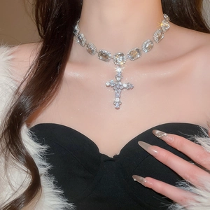 Close-up of luxury cross pendant necklace with rectangular gemstones on a model