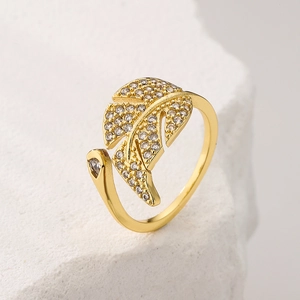 Macro shot of gold-plated leaf ring with cubic zirconia on white textured stone background