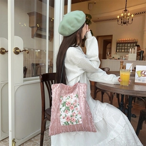 Close-up of pink velvet tote bag featuring a floral pocket and white brand label
