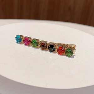 Macro detail of colorful rhinestones set on a gold alloy hair clip for women