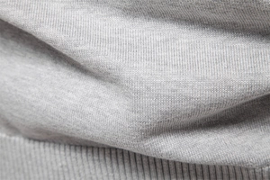Gros plan sur la texture en maille de coton gris avec bord-côte sur le pull