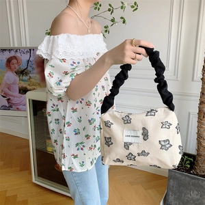 Detail of canvas tote bag featuring black butterfly embroidery and ruched strap texture