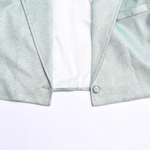 Détail de l'ourlet du blazer pailleté bleu argenté avec bouton, poche et doublure blanche