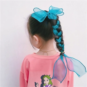 Blue organza bow hair clip with long ribbons shown on child's braided hairstyle