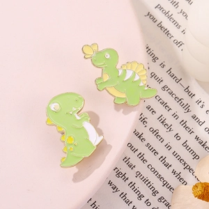 Pair of green cartoon dinosaur enamel pins featuring a stegosaurus and cute T-Rex badge
