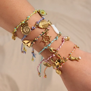 Colorful woven beach bracelets with 18k gold plated nautical ocean charms on a wrist