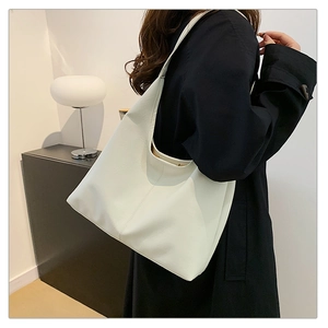 Dettaglio della trama della grande borsa hobo bianca in pelle indossata con cappotto