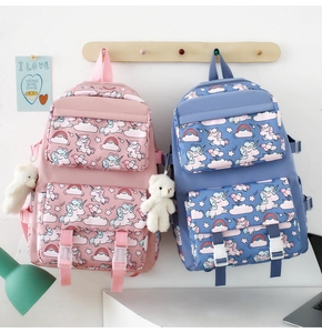 Detail of pink and blue unicorn nylon backpacks with cute bear charms on wooden hooks