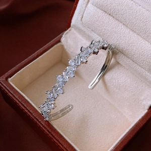 Detail of silver irregular open bangle with zircons on velvet lining inside jewelry box