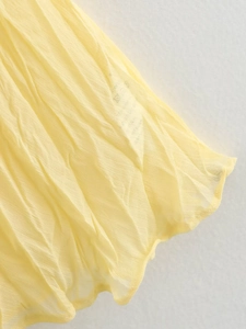 Vue détaillée du tissu en mousseline plissée jaune avec couture fine sur le bas de jupe