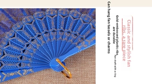 Detailed macro of a blue folding fan featuring golden floral plastic ribbing and metal loop
