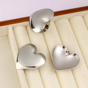 Detailed view of silver heart-shaped earrings on a beige velvet jewelry display tray