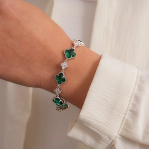 Détail du bracelet trèfle avec pierres vertes et oxydes de zirconium au poignet