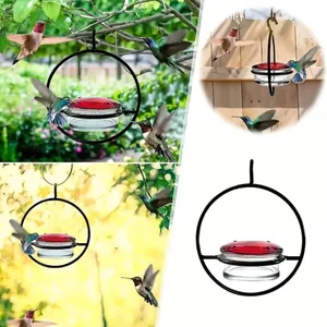Hanging metal hummingbird feeder with a clear glass bowl and red lid for garden use
