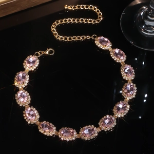Elegant multi-layer gold necklace featuring pink oval crystals on a black mirror background