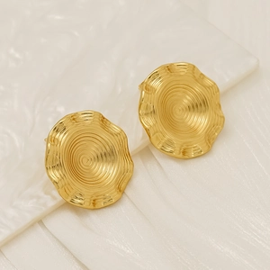 Macro detail of gold-plated circular earrings with irregular spiral texture on silk background