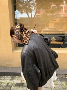 Street style view of oversized leopard print scrunchie paired with a black leather jacket