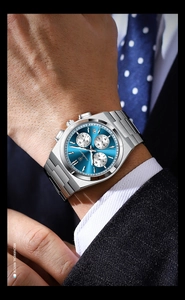 Close-up of a silver mechanical watch with blue chronograph dial on a man's wrist