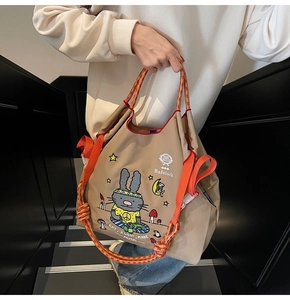 Detailed view of canvas tote bag featuring cartoon rabbit print and orange braided handles