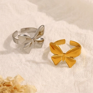 Close-up of gold and silver bow-shaped open rings on textured fabric background