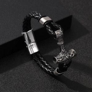 Braided leather Viking bracelet with silver Mjolnir hammer magnetic clasp on dark background
