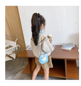 Blue mini bunny crossbody bag shown on a child model to demonstrate size and fit