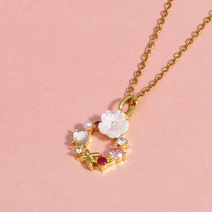 Détail du pendentif couronne dorée avec fleurs blanches, perles et pierres colorées