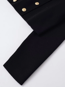 Macro detail of black knit cardigan featuring luxury gold embossed metal buttons