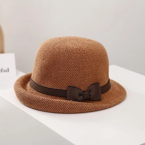 Macro view of woven straw texture and dark brown ribbon bow on the sun hat