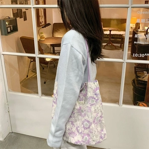 Detailed side view of floral lace tote bag with purple straps in a cafe setting