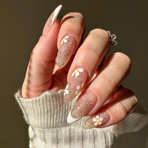 Detailed view of almond-shaped nails with white daisy patterns and French tips