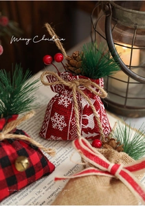 Close-up of Christmas linen gift bags with pine cones and berries on vintage books