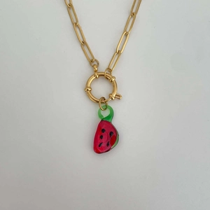 Close-up of golden paperclip chain necklace featuring a red watermelon slice pendant