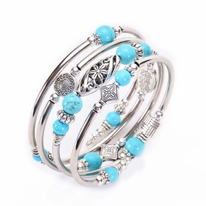 Detail of bohemian multilayer turquoise bead bracelet with silver tone charms