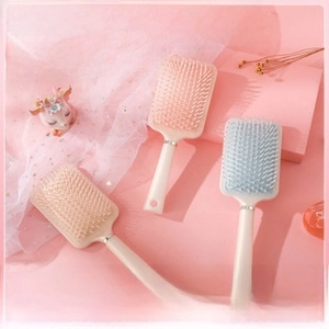 Detail of cream-colored air cushion hairbrushes with massaging bristles and matte finish