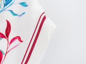 Macro view of tropical leaf print fabric with red and blue floral patterns and stripes