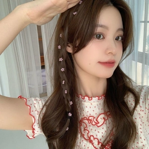 Dettaglio di ciondoli per capelli a fiore rosa intrecciati in una treccia su modella