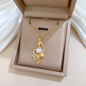 Detailed shot of a gold eagle wing necklace with white pearl and sparkling crystals in a gift box