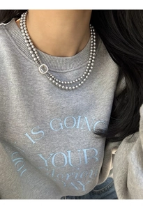 Detail of a double-layered necklace with grey glass pearls and a square shell-inlay pendant