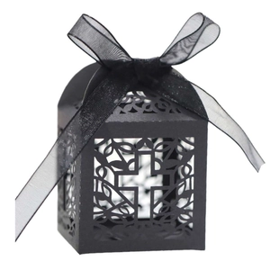 Close-up of black laser-cut favor box with a cross pattern and organza ribbon bow