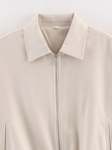 Detail of beige zip-up jacket collar showing twill cotton texture and silver metal zipper