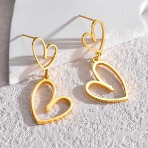 Detailed view of gold-plated hollow double heart earrings on textured stone surface
