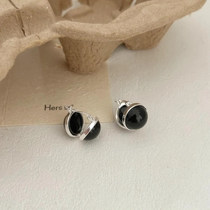 Detail of 925 sterling silver earrings with black onyx round beads on a textured background