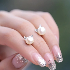 Close-up of cat ear pearl earrings in silver finish worn on fingers for detail