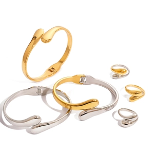 Minimalist gold and silver stainless steel jewelry set with teardrop crossover rings and bangles