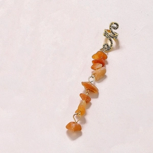 Macro detail of natural orange stone pendant hair ring with silver metal spiral clip
