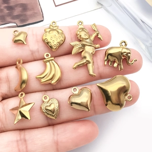 Pendentifs en acier doré en forme de cœur et de fruit présentés sur une main