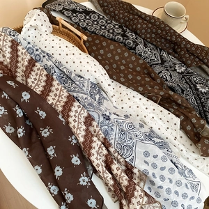Detail shot of vintage silk scarves with floral and polka dot patterns in a woven basket