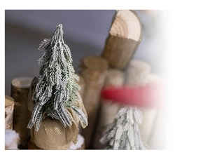 Close-up of mini snowy Christmas tree with pine needles and rustic burlap base detail