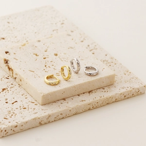 Close-up of gold and silver S925 sterling silver hoop earrings on natural stone slabs